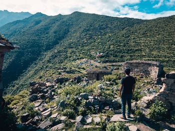 Rear view of man looking at mountains against sky