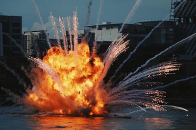 Explosion on harbor in sea by city against sky