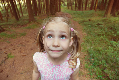 Cute girl looking up standing in forest