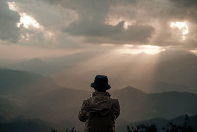 A man is taking the photo on the peak and looking at the sky explosions