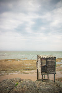 Bench on beach against sky