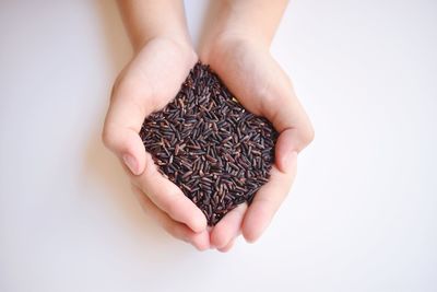 Close-up of hand holding coffee cup over white background