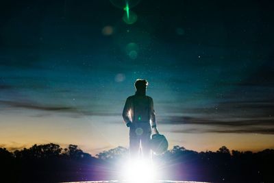 Man wearing space suit standing against sky during dusk