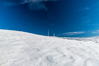 Snow covered field against blue sky