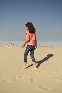 Full length of a girl on the beach against clear sky