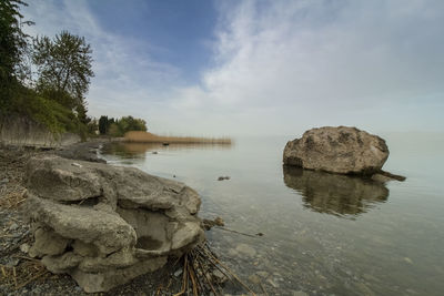 Rocks by lake against sky