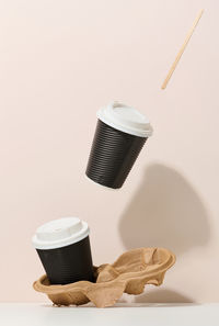 Two brown cardboard cups with a white plastic lid. disposable tableware levitates against a 