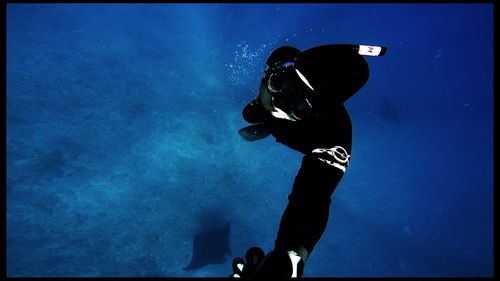 Low angle view of silhouette man against blue sky