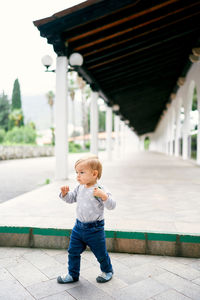 Full length of cute boy standing against built structure