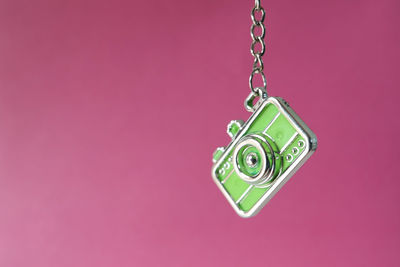 Close-up of heart shape decoration hanging over pink background