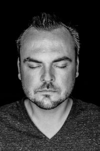 Close-up of mid adult man with eyes closed against black background