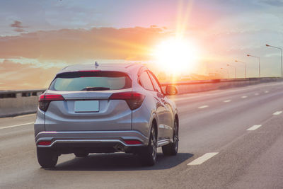 Cars on road against sky during sunset