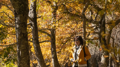 Rear view of woman standing in forest during autumn