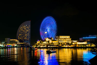 Illuminated city by river at night