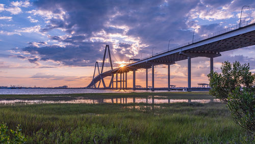 Bridge over sea against cloudy sky