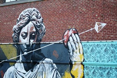 Close-up of man with graffiti on brick wall