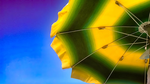 Low angle view of yellow leaf against blue sky