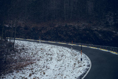 Snow covered road by trees in forest