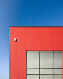 Low angle view of red building against clear blue sky