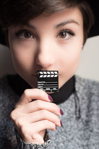 Close-up portrait of young woman holding film slate toy