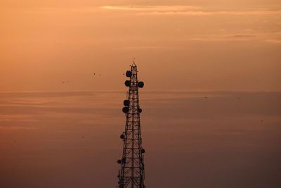 Silhouette of communications tower against sky during sunset