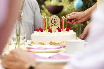 Hand lighting candles on 80th birtday cake