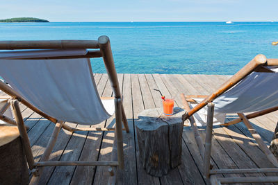 Chairs on beach by sea against sky