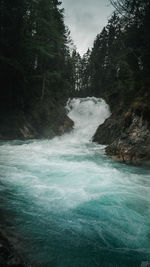 Scenic view of waterfall in forest against sky