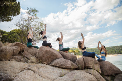 People sitting on rock against sky