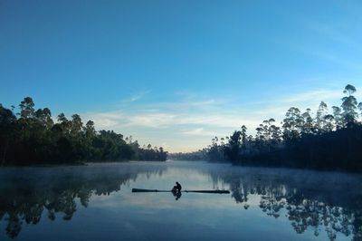 Silhouette man in lake against sky