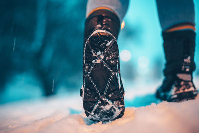 Low section of person walking on snow land