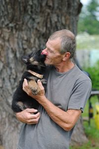 Man carrying puppy by tree