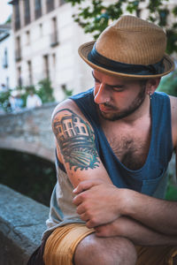 Mid adult man looking at his tattoo on arm while sitting in city