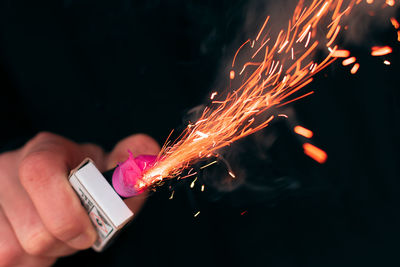 Close-up of hand holding fire crackers at night