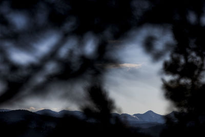 Low angle view of storm clouds over silhouette mountains