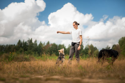Man and dog standing on field against sky