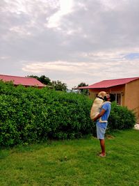 Rear view of man standing on field against sky