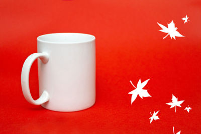 Close-up of mug with christmas decoration on red background