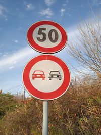 Road sign on field against sky