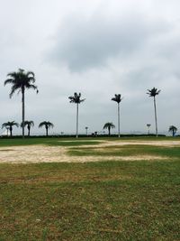 Grassy field against cloudy sky