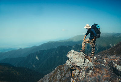 Backpack man standing on cliff against sky