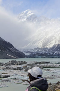 Woman at lakeshore against snowcapped mountains