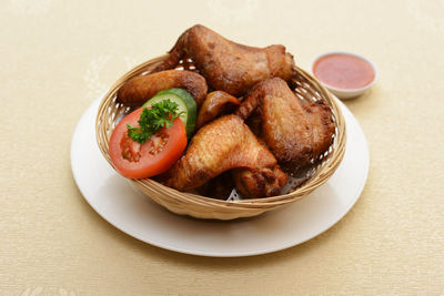Close-up of fried chicken wing served in wicker basket