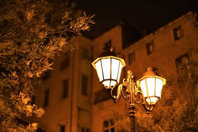 Low angle view of illuminated street light against building at night