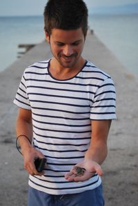 Close-up of young man using mobile phone at beach