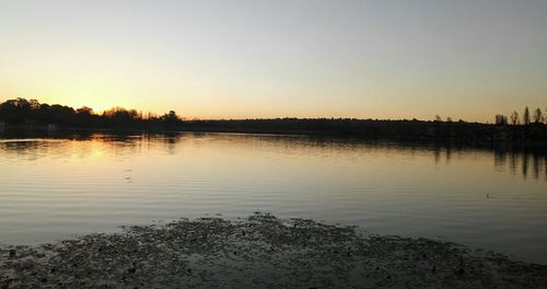 Scenic view of lake against clear sky during sunset