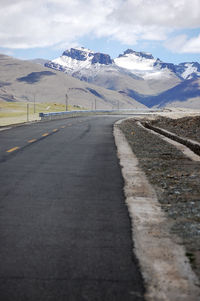 A flat newly built unmanned asphalt road leads to the foot of the snowy mountain ahead