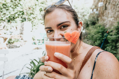 Woman holding cocktail in front of face