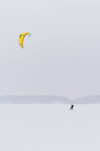 Person paragliding over sea against clear sky