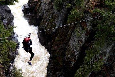 Full length of man zip line over river